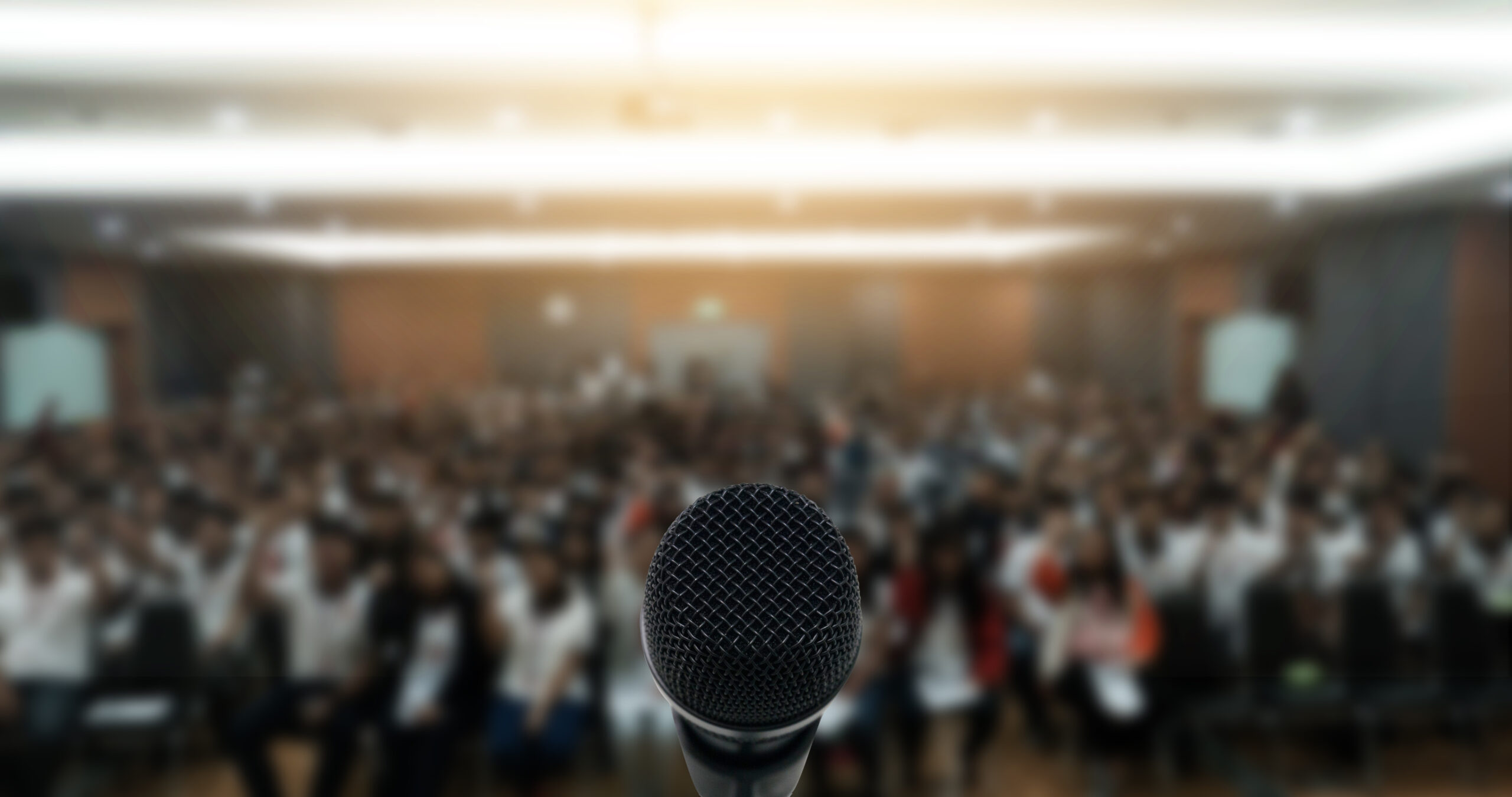 Microphone over the Abstract blurred photo of conference hall or seminar room with attendee background,Small Business training concept,Public speaking