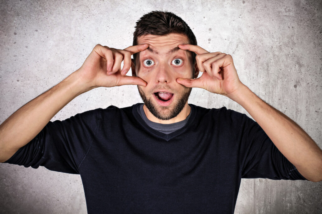 homme qui écarquille les yeux avec ses doigts